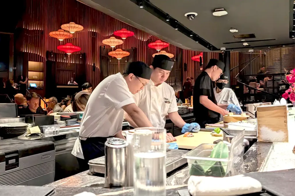 Chefs preparing sushi behind a counter at an upscale restaurant, highlighting the craft and live cooking experience that transforms modern dining.