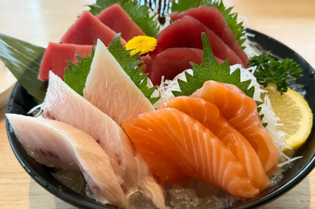 A variety platter of fresh salmon, tuna, and yellowtail sashimi served on a bed of ice with lemon and shiso leaves at Sushi Tei, Singapore.