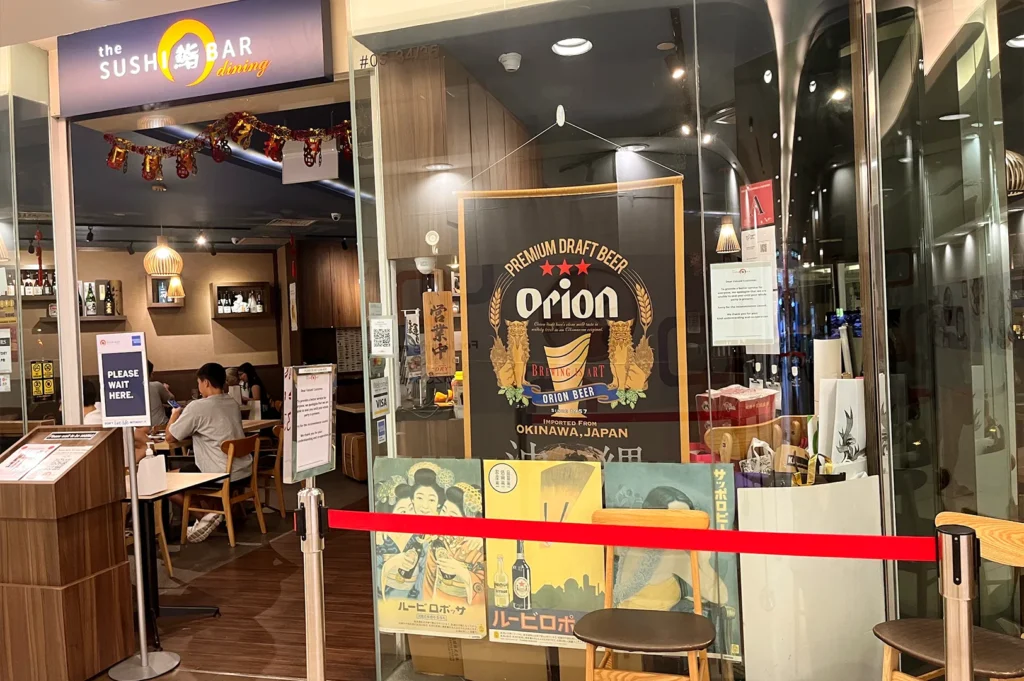 Exterior facade of The Sushi Bar at Ngee Ann City, showcasing the restaurant entrance with Japanese-style signage and a welcoming atmosphere for diners.
