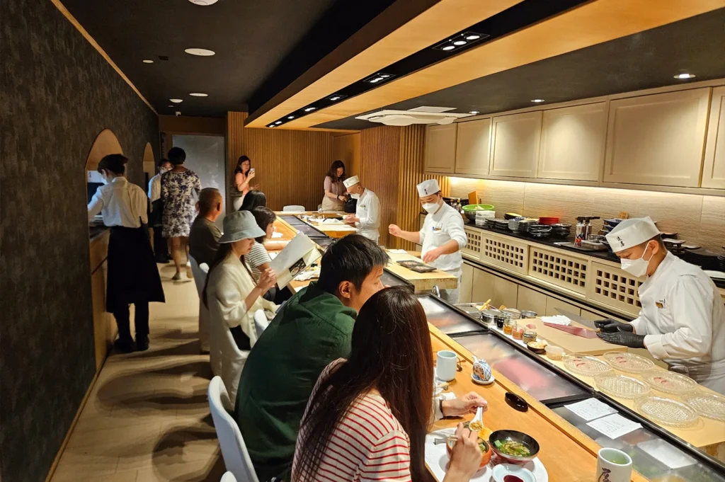 Chef preparing fresh sashimi at the wooden sushi counter in Tatsuya restaurant, located inside Goodwood Park Hotel, Singapore.