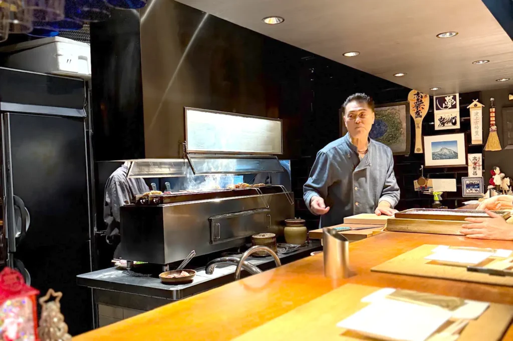 A chef attentively managing the hot charcoal grill station at Kazu Sumiyaki Singapore, bringing authentic Japanese yakitori traditions to life.