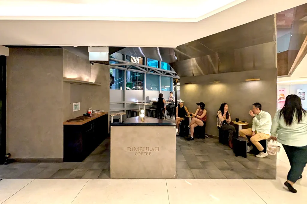 The minimalist and cozy interior of Dimbulah Coffee, where customers are seated and enjoying their coffee in Republic Plaza.