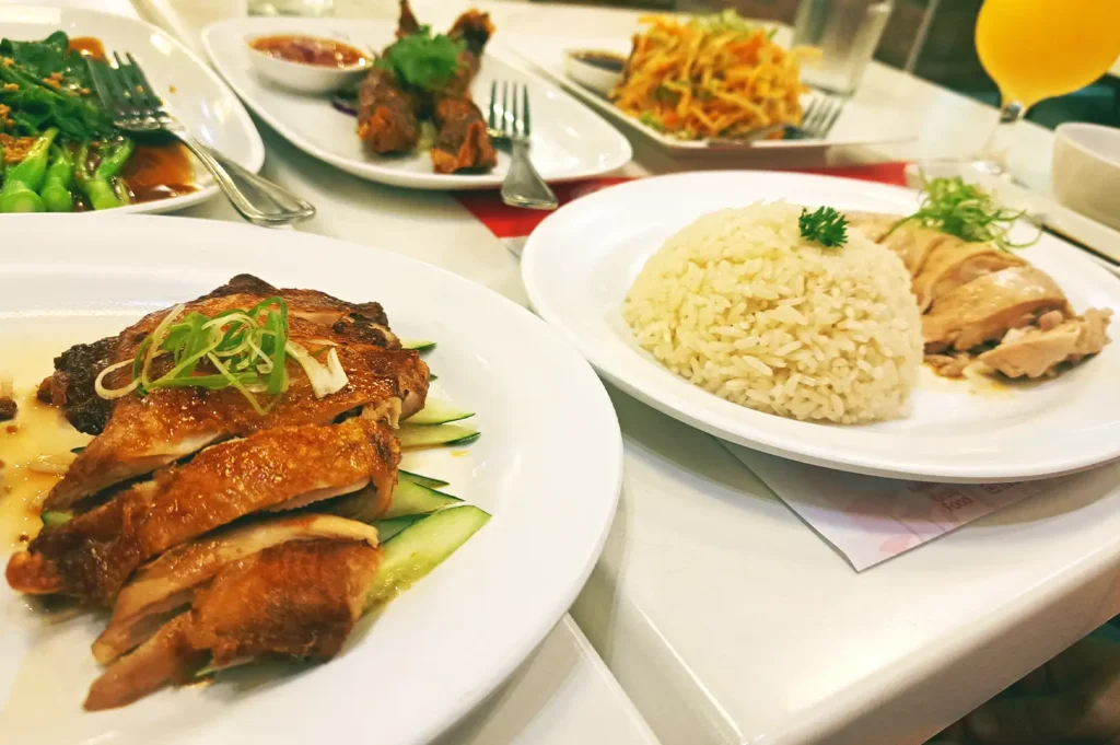 A table spread featuring various shared dishes, including sliced roasted chicken, plates of rice, and vegetable sides, reflecting the joy of collecting restaurant names and turning small food discoveries into personal memories over time.