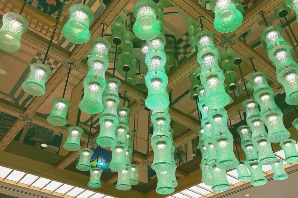 Elegant cluster of textured green glass pendant lights hanging from a wooden ceiling grid inside the restaurant.