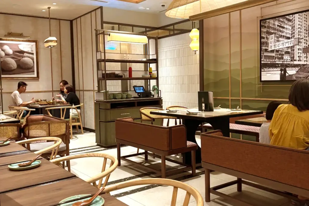 Refined interior dining space at Tim Ho Wan PEAK showing comfortable seating, wooden partitions, and warm ambient lighting.