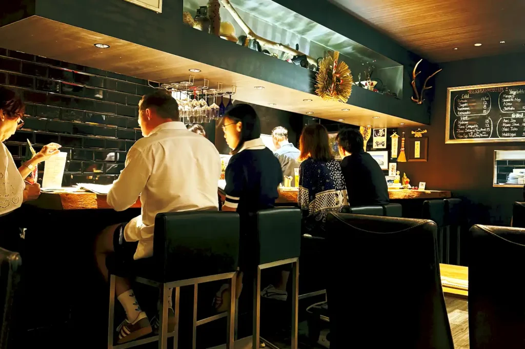Customers seated along the warm wooden counter inside Kazu Sumiyaki, enjoying an intimate dining experience with views of the open kitchen.