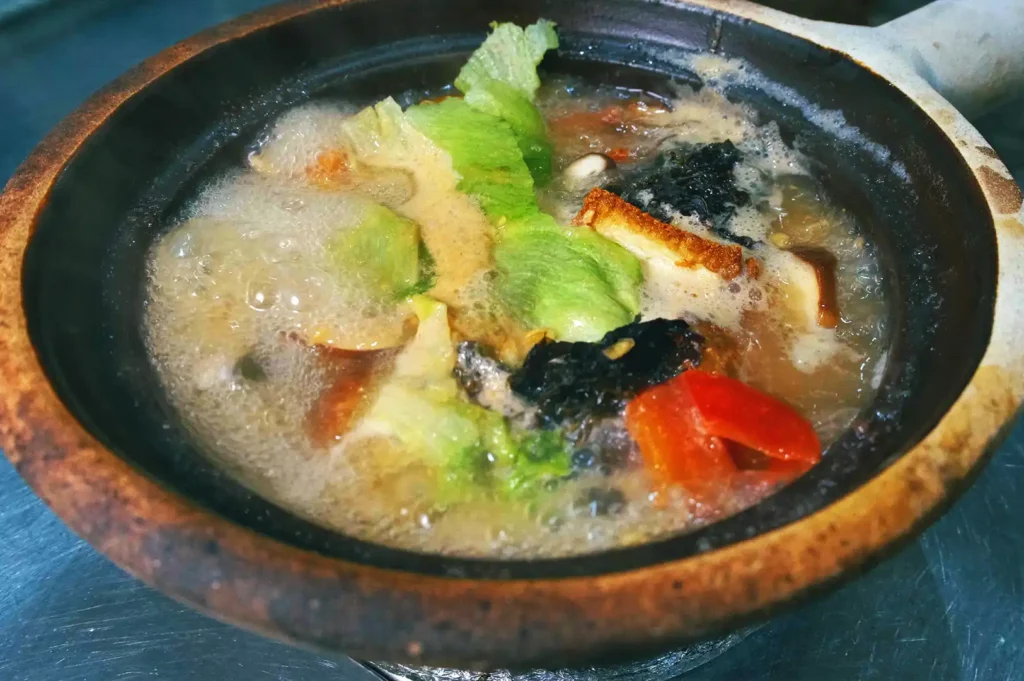 A bubbling claypot of nourishing pomfret soup filled with fresh fish, leafy greens, and mushrooms at Hup Lok, reflecting three generations of seafood expertise.