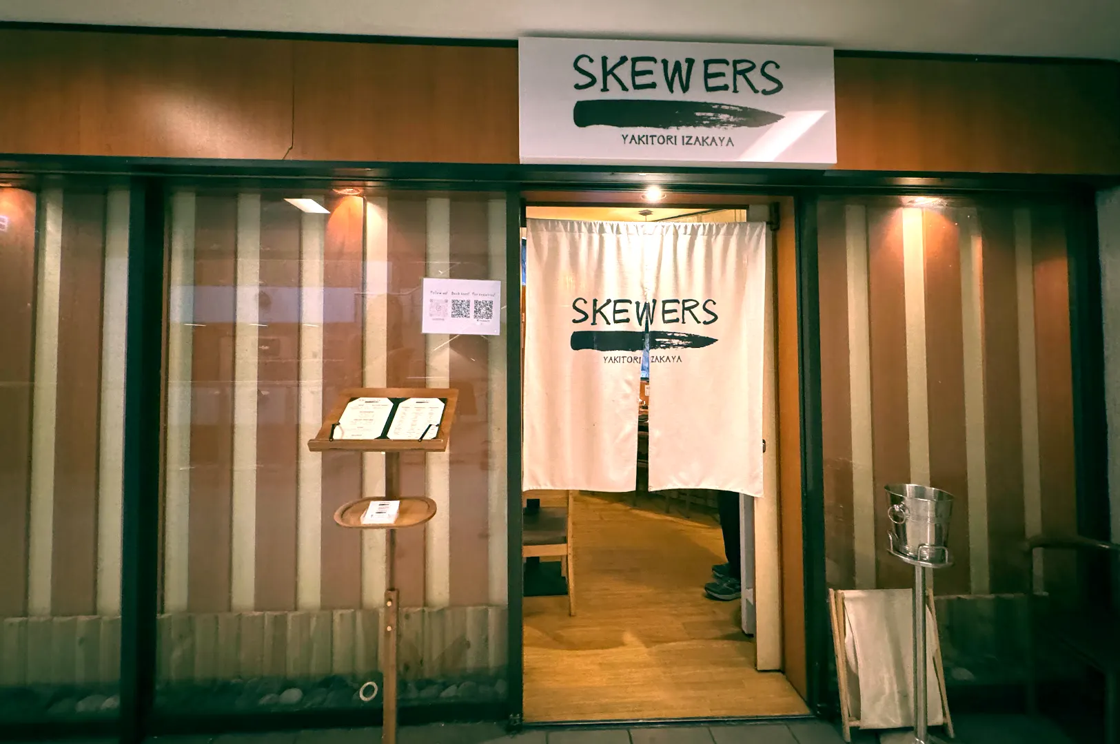 Wooden exterior facade and white noren entrance curtain of Skewers Yakitori Izakaya located inside Cuppage Plaza.