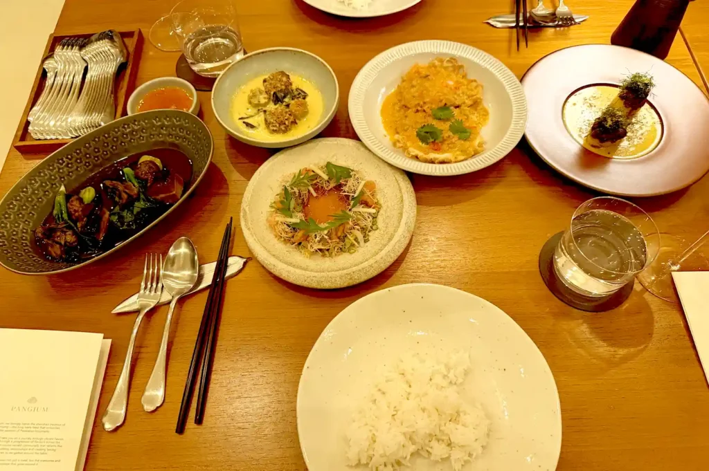 An elaborate spread of the Tok Panjang idea menu sets at Pangium, featuring a rich assortment of traditional Peranakan dishes, communal bowls, and fragrant rice.