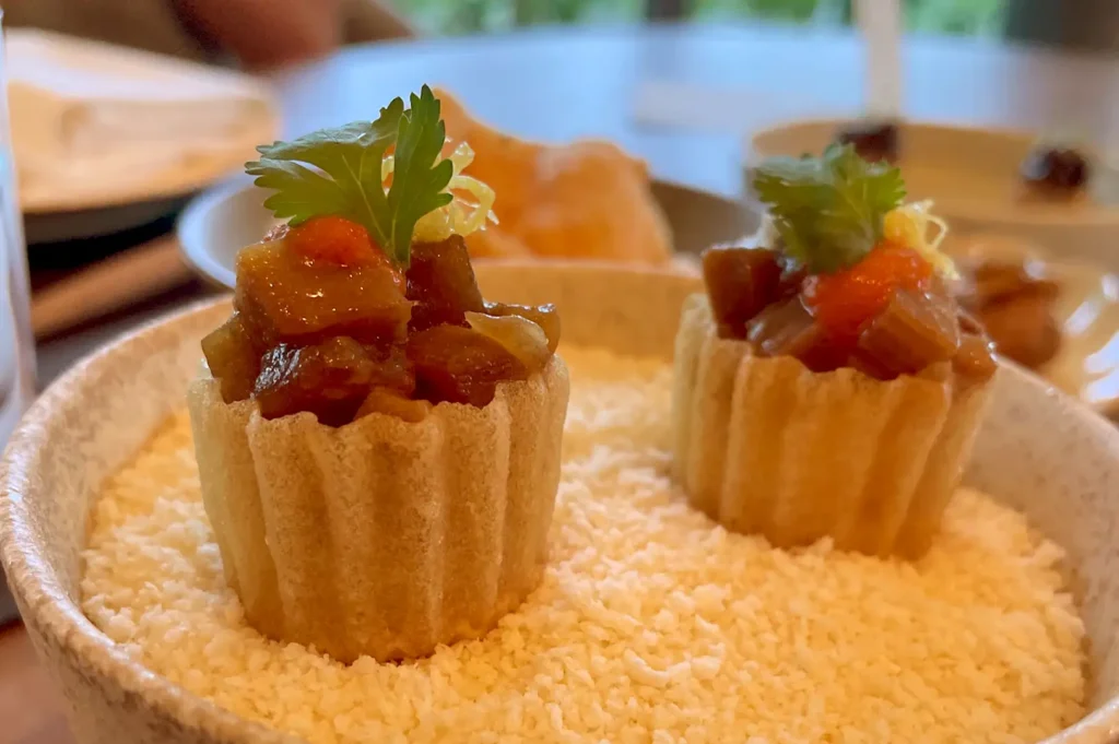 Crispy and intricate Kueh Pie Tee shells filled with savory fillings and fresh garnishes, presented as an exquisite Peranakan bite-sized starter.