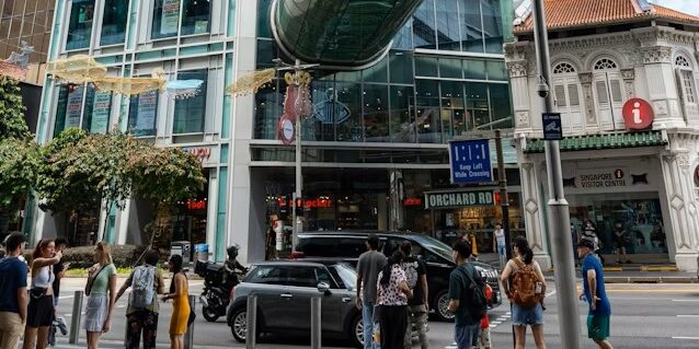Shoppers crossing the street along Orchard Road, Singapore’s iconic retail and dining destination lined with modern buildings and cafes.